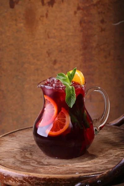 Wein aus Sangrija mit einer Orange in einem transparenten Krug auf einem hölzernen — Stockfoto