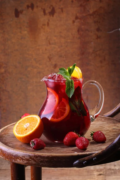 Wine of Sangrija in a transparent jug on a wooden table with an — Zdjęcie stockowe