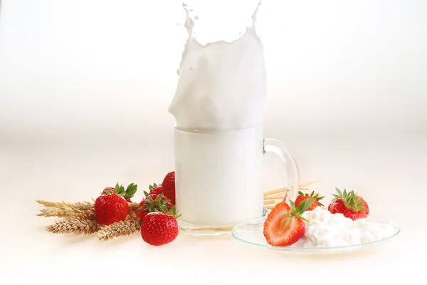 Leche y fresa sobre un fondo blanco, salpicadura de leche en un tranvía — Foto de Stock