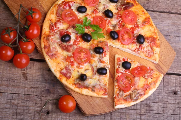 Pezzo di pizza e pizza da un salame, un prosciutto e pomodori su — Foto Stock