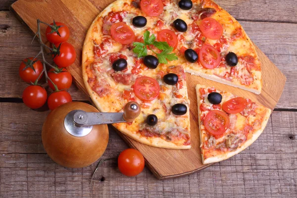Pezzo di pizza e pizza da un salame, un prosciutto e pomodori su — Foto Stock