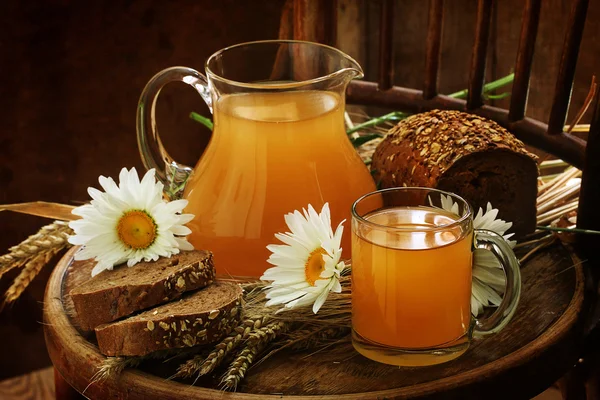 Kvass (Kvas) in a transparent jug, rye bread and camomiles on a 