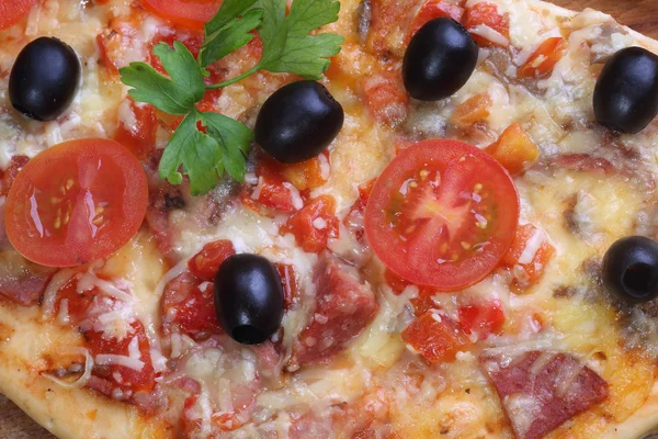 La pizza del salami, el jamón y los tomates sobre la mesa de madera — Foto de Stock