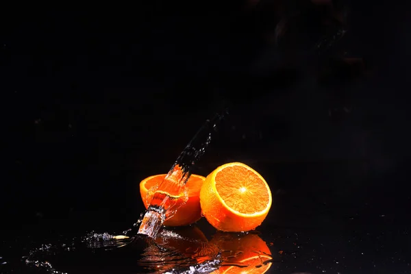 La naranja sobre el fondo negro, el agua fluye sobre las naranjas —  Fotos de Stock