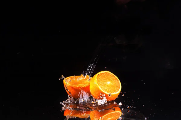 La naranja sobre el fondo negro, el agua fluye sobre las naranjas —  Fotos de Stock