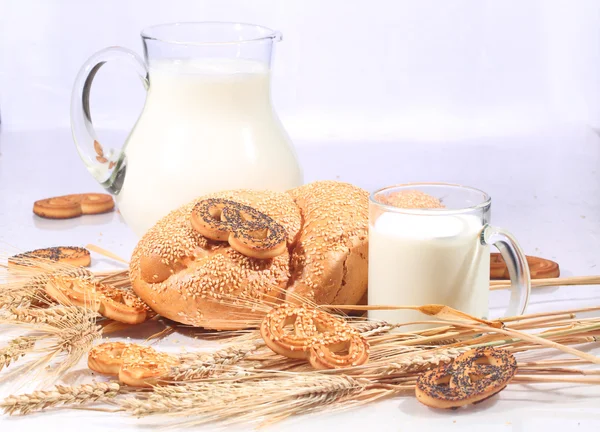 Milk in a transparent jug and a roll from wheat flour of a house — Stock Photo, Image