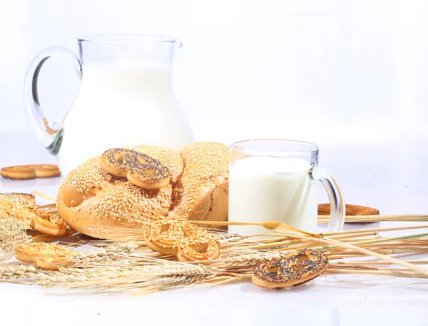 Milk in a transparent jug and a roll from wheat flour of a house — Stock Photo, Image