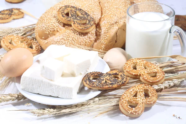 Stilleven met melk in een transparante mok, een broodje en een brynza — Stockfoto