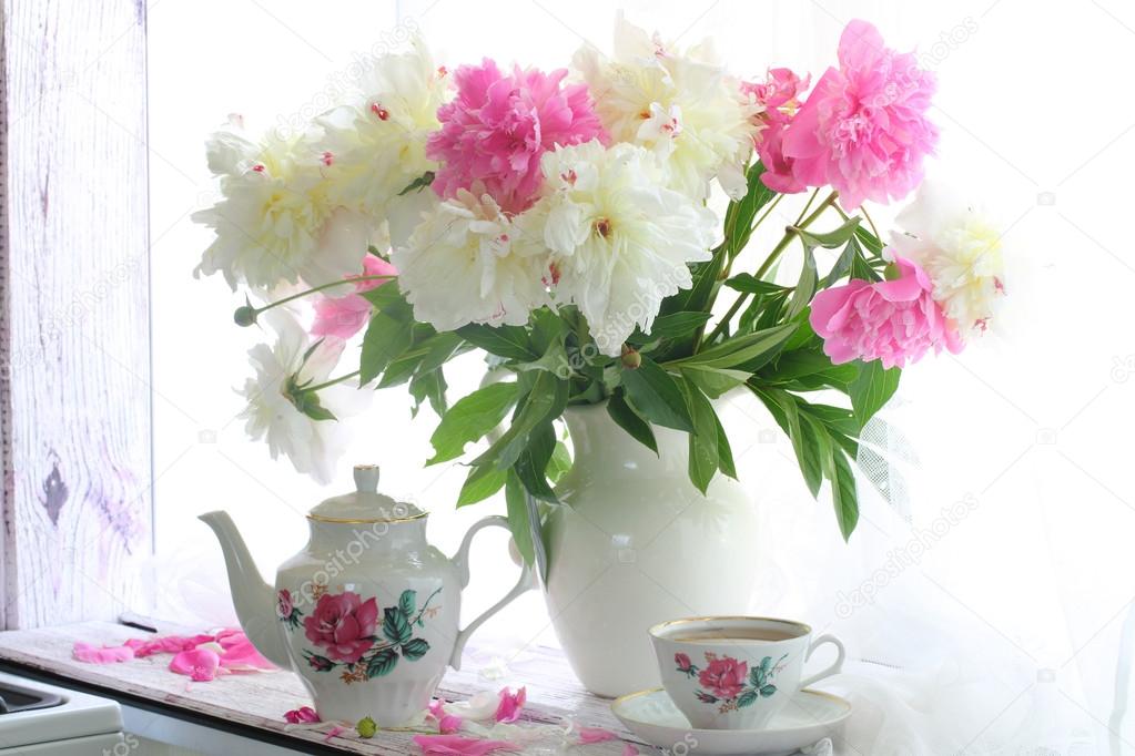 Still-life with tea and a bouquet of peonies on a white window s