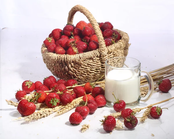 Milk in a transparent mug and a strawberry in a wattled basket o — Stock Photo, Image