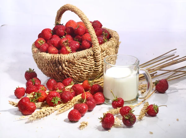 Milk in a transparent mug and a strawberry in a wattled basket o — Stock Photo, Image