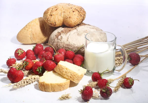 Milk in a transparent mug, bread and a strawberry on a white bac — Stock Photo, Image