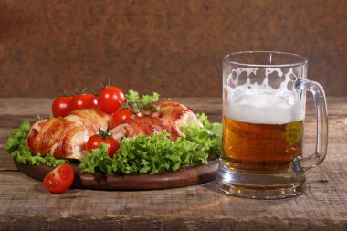 Gönderilmiş pastırmalı tavuk Tokmaklar ve şeffaf bir kupa bira