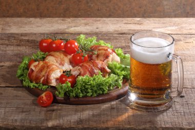 Bira şeffaf bir kupa ve pastırma bir ahşap üzerine tavuk Tokmaklar