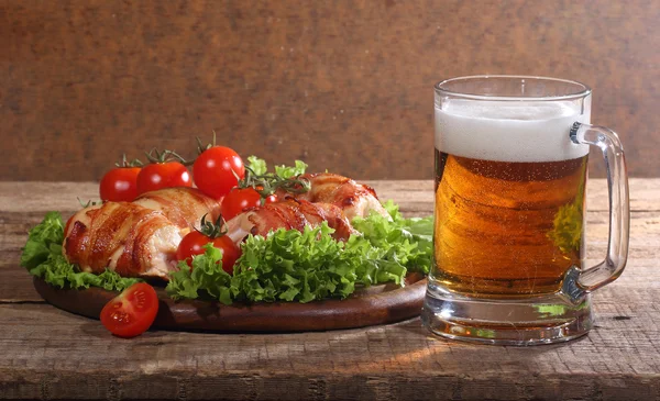 Gönderilmiş pastırmalı tavuk Tokmaklar ve şeffaf bir kupa bira