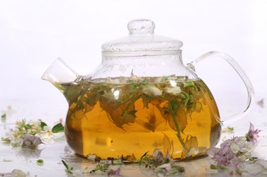  Otlar ve nane beyaz ba üzerinde şeffaf bir demlik çay