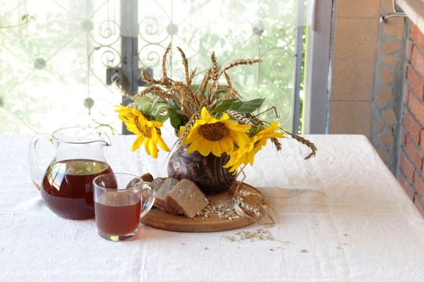 Ramo de girasoles en un jarrón de cerámica y kvas en un tr — Foto de Stock
