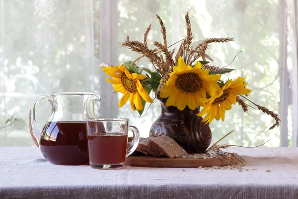 Stilleven met kvas (kvas) en zonnebloemen — Stockfoto