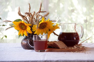 Kvas (kvas) şeffaf bir sürahi ve ayçiçeği bir buket