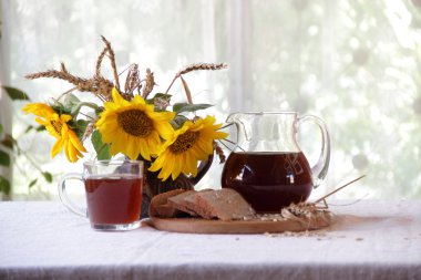 Kvas (kvas) şeffaf bir sürahi ve ayçiçeği bir buket