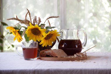 Kvas (kvas) şeffaf bir sürahi ve ayçiçeği bir buket