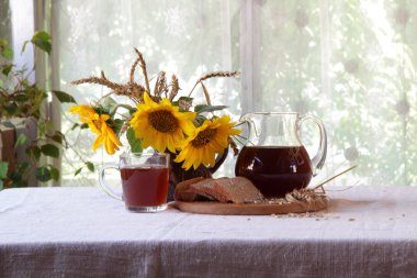 Kvas (kvas) şeffaf bir sürahi ve ayçiçeği bir buket