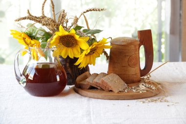 Kvas (kvas) şeffaf bir sürahi, ahşap bir kupa ve bir buket