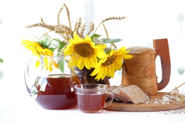 Kvas (kvas) şeffaf bir sürahi, ahşap bir kupa ve bir buket