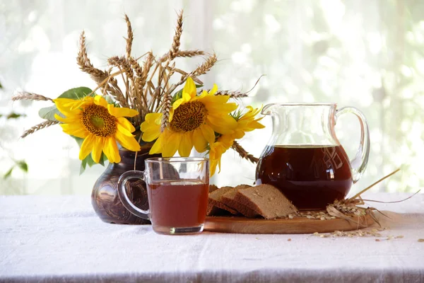 Kvas (kvas) en una jarra transparente y un ramo de girasoles —  Fotos de Stock