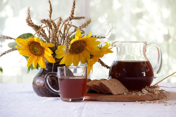 Kvas (kvas) en una jarra transparente y un ramo de girasoles —  Fotos de Stock