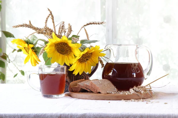 Квас (kvas) в прозорому глечику і букет соняшників — стокове фото