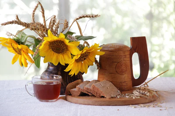 Квас в деревянной кружке, хлеб и букет подсолнухов — стоковое фото