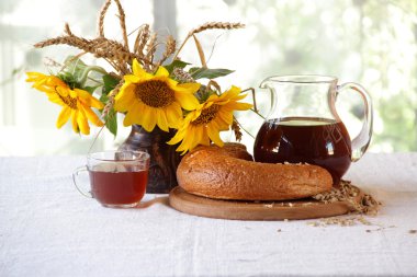 Kvas (kvas) şeffaf bir sürahi, ekmek ve bir buket sunflo