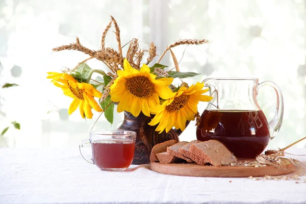 Kvass (kvas) en una jarra transparente, pan y un ramo de sunflo —  Fotos de Stock