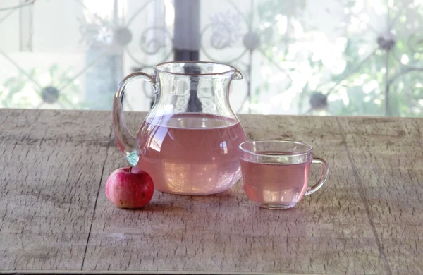 Apple compote in a transparent jug on a wooden table — Stock Photo, Image