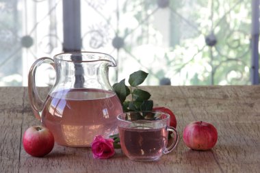 Elma kompostosu, şeffaf bir sürahi taze elma ve bir gül