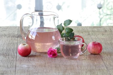 Elma kompostosu, şeffaf bir sürahi taze elma ve bir gül