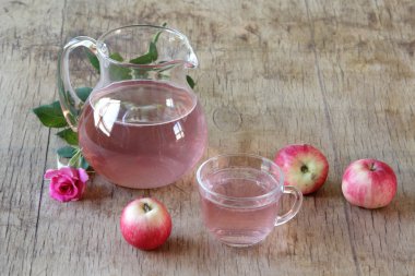 Elma kompostosu, şeffaf bir sürahi taze elma ve bir gül