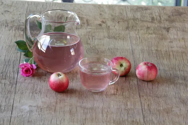 Elma kompostosu, şeffaf bir sürahi taze elma ve bir gül
