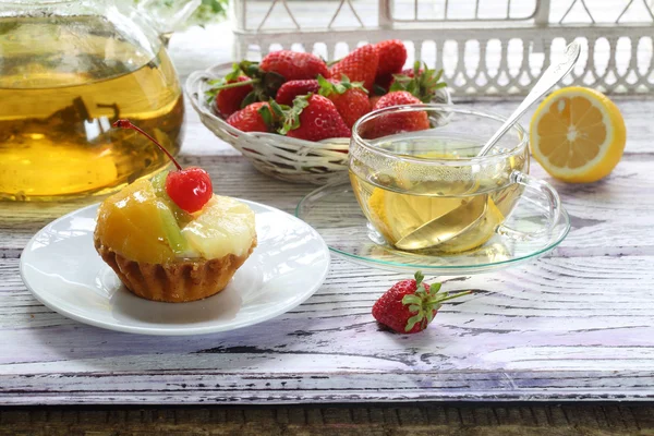 Торт с фруктами и чаем с лимоном в прозрачной чашке — стоковое фото