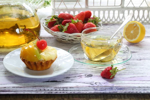 Cake with fruit and tea with a lemon in a transparent cup — Stock Photo, Image