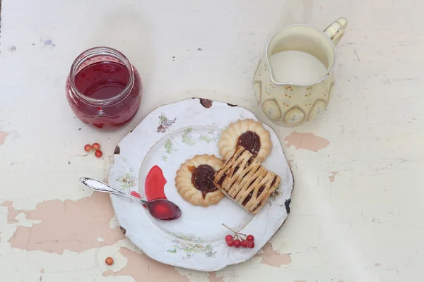 Kekse in einem alten Teller, eine Kanne mit Sahne und Marmelade in transparenten — Stockfoto