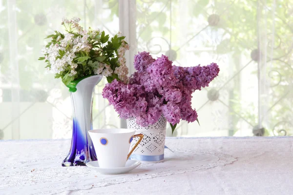 Té en una hermosa taza y un ramo de ramas lila — Foto de Stock