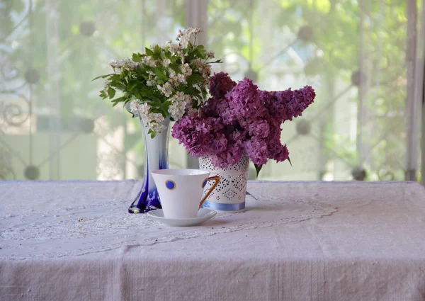 Tee in einer schönen Tasse und ein Strauß aus Fliederzweigen — Stockfoto