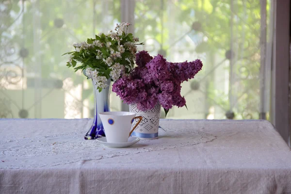 Tee in einer schönen Tasse und ein Strauß aus Fliederzweigen — Stockfoto
