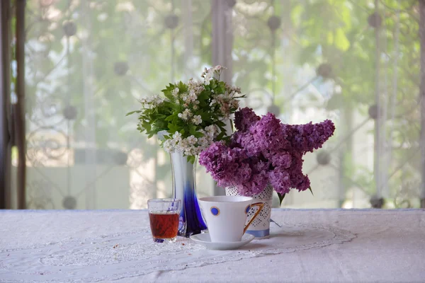 Stillleben mit Tee, Wein und Fliederstrauß — Stockfoto