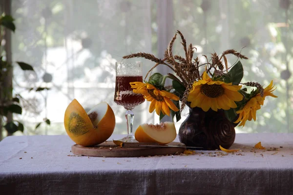 Rotwein in einem schönen Glas, eine reife Melone und ein Strauß Sonne — Stockfoto
