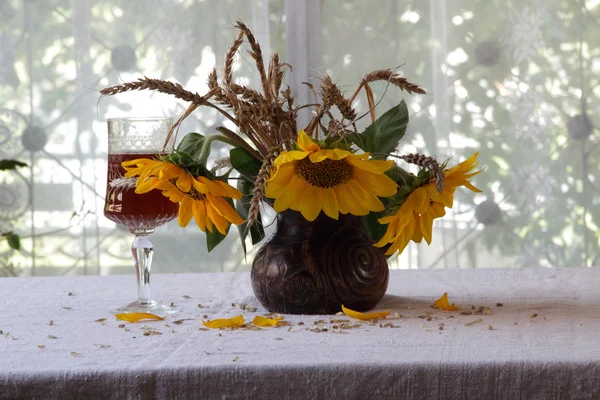 Rode wijn in een mooi glas en een boeket van zonnebloemen — Stockfoto