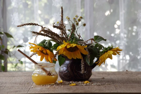 Honig in transparenter Bank und der Strauß Sonnenblumen — Stockfoto