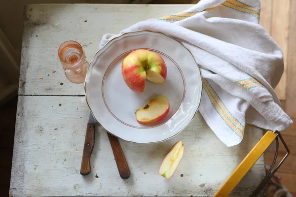 Червоне яблуко на тарілці і горілка в прозорому винному склі — стокове фото